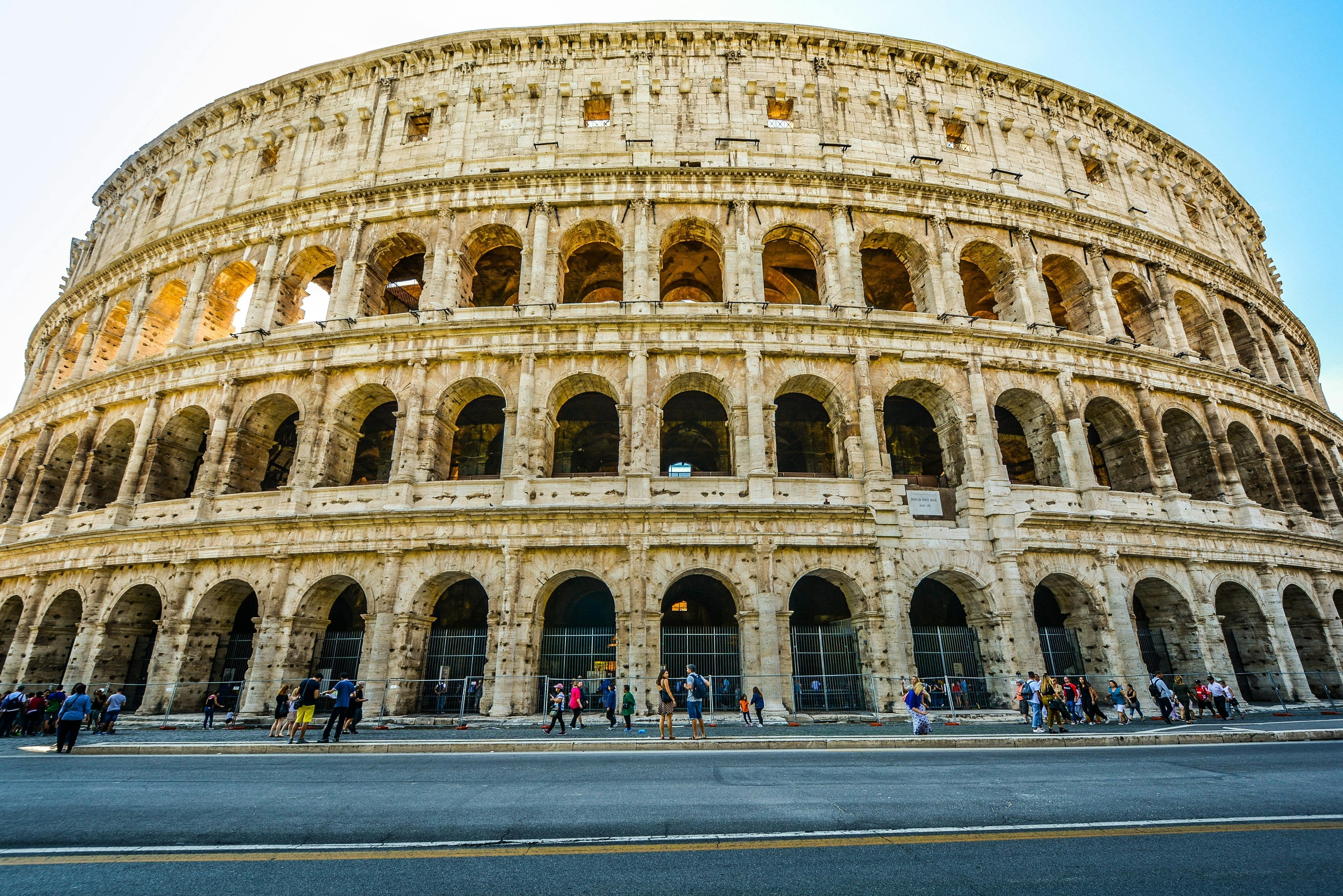 Colosseum with people walking around outside it.