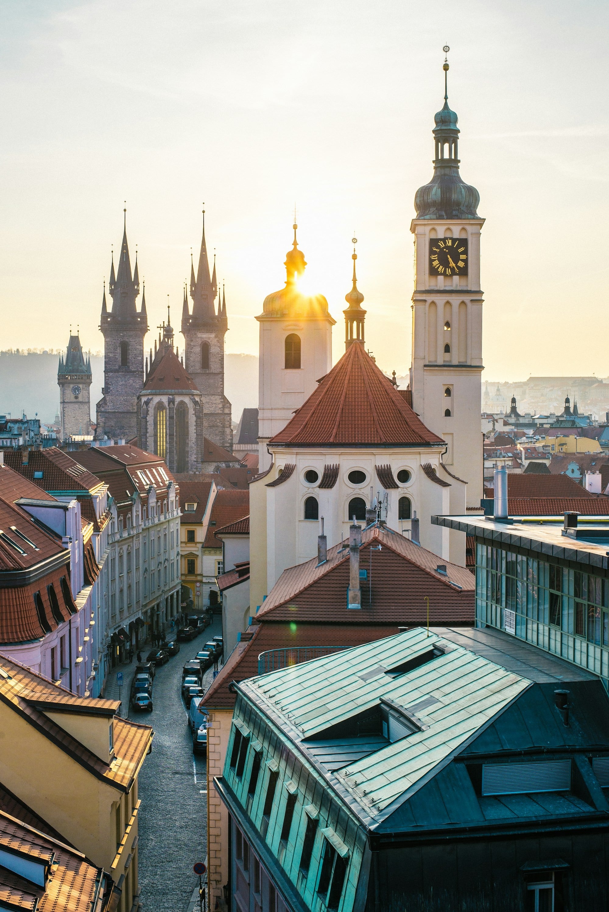 tops of buildings and clock tower with the sun setting
